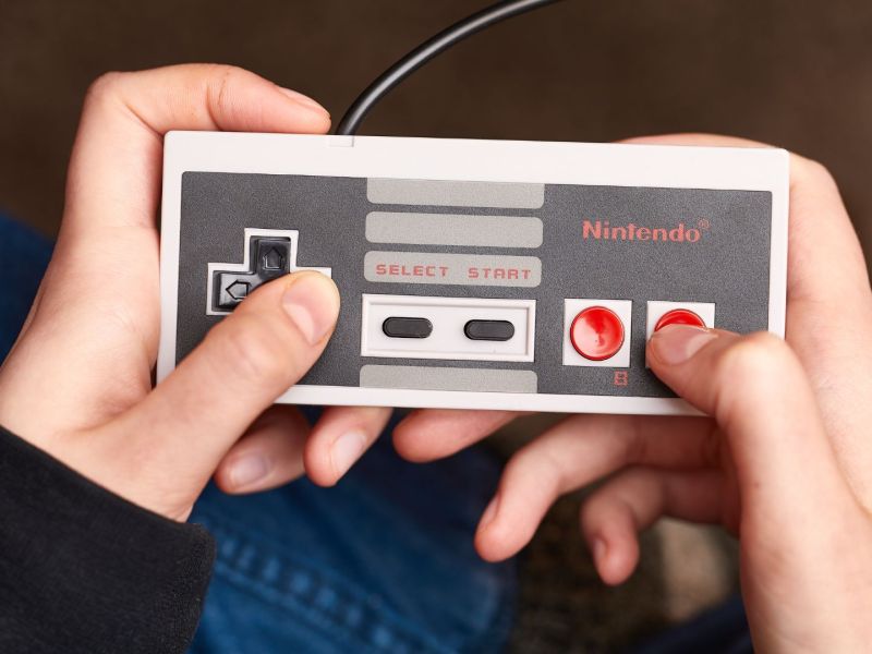 Person hÃ¤lt einen NES-Controller in der Hand.