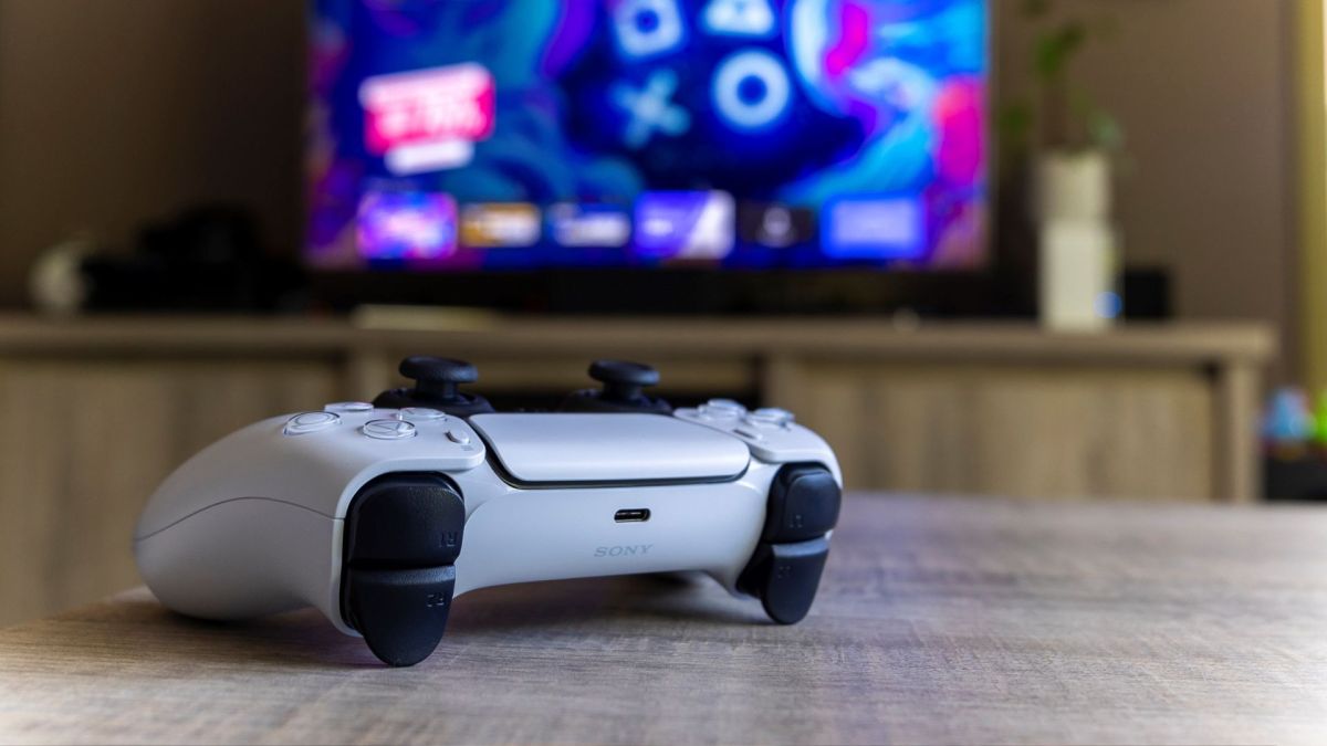 PS5-Controller vor einem Bildschirm mit PlayStation-Symbolen.