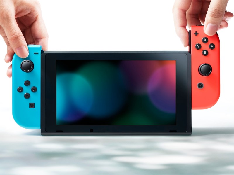 Eine Nintendo Switch mit einem roten und blauen Joy-Con und zwei HÃ¤nden.